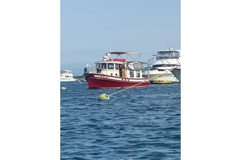 Slide: The Image of Red 1996 Nordic Tug 32 boat anchored on calm blue water. - 2