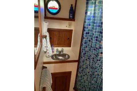 Slide: The Image of Bathroom interior of a 1996 Nordic Tug 32 with sink and mosaic shower curtain. - 24