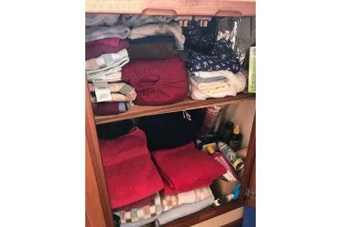 Slide: The Image of Storage cabinet on a 1996 Nordic Tug 32, filled with neatly organized towels and supplies. - 28