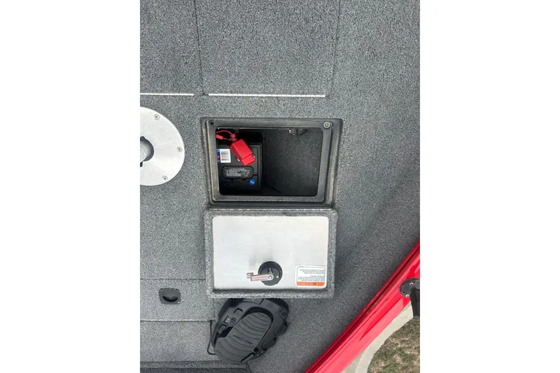 Slide: The Image of 2016 Tracker Pro Guide V-16 SC boat battery compartment with secure latch and red trim. - 20