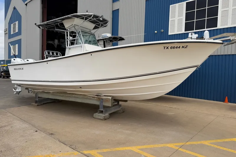 Slide: The Image of 1997 Regulator 26 Center Console boat on display outside a blue warehouse. - 1