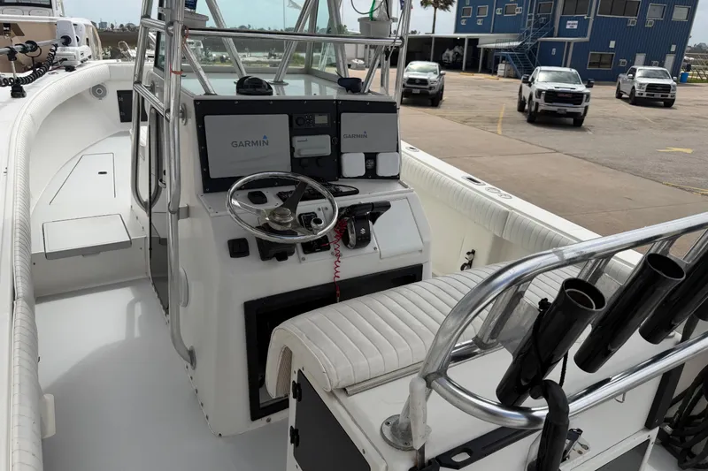 Slide: The Image of 1997 Regulator 26 Center Console boat with Garmin navigation, docked near trucks. - 11