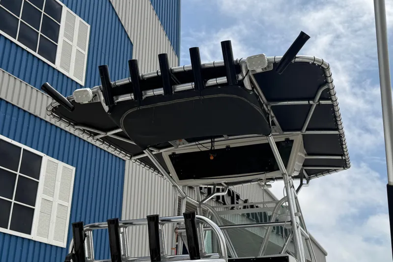 Slide: The Image of 1997 Regulator 26 Center Console boat with T-top and rod holders, docked near a blue building. - 12