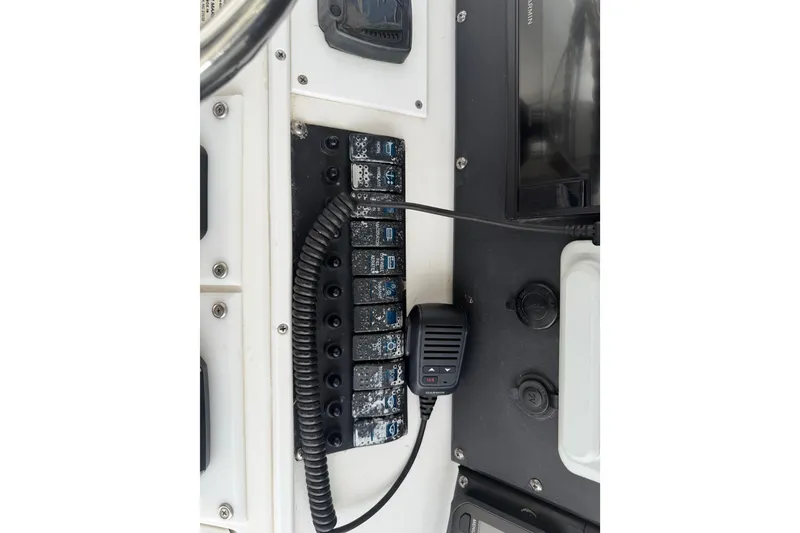 Slide: The Image of Control panel of a 1997 Regulator 26 Center Console boat with switches and a microphone. - 13