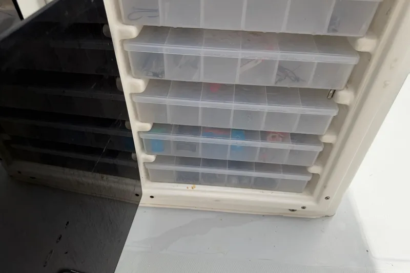 Slide: The Image of Storage compartments on a 1997 Regulator 26 Center Console boat, featuring organized tackle boxes. - 42