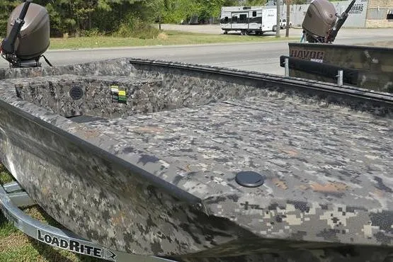 Slide: The Image of Camouflage-patterned 2026 Havoc 1553 VJST boat on LoadRite trailer, parked outdoors. - 3