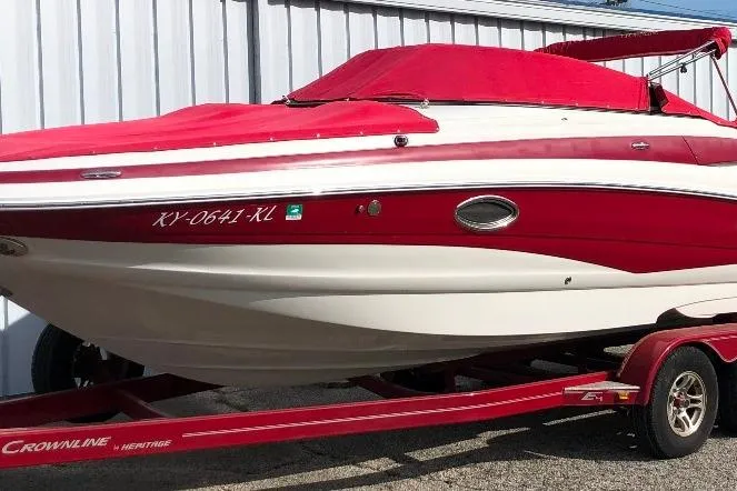 Slide: The Image of 2012 Crownline Eclipse E4 boat with red cover on trailer, parked outdoors. - 13