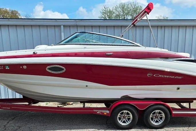 Slide: The Image of 2012 Crownline Eclipse E4 boat on trailer, red and white design, parked outdoors. - 2