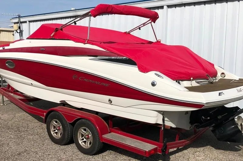 Slide: The Image of 2012 Crownline Eclipse E4 boat with red cover on trailer, parked outdoors. - 26