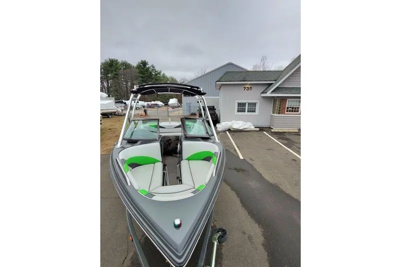 Slide: The Image of 2009 Moomba Mobius LSV boat with green accents parked outside a building. - 3