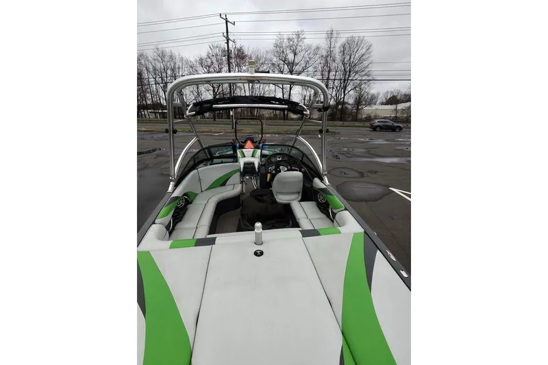 Slide: The Image of 2009 Moomba Mobius LSV boat interior with green and white seating, parked outdoors. - 4
