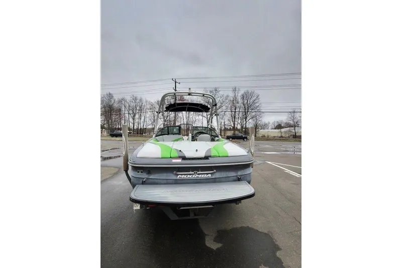 Slide: The Image of 2009 Moomba Mobius LSV boat with green accents, parked on wet pavement. - 5