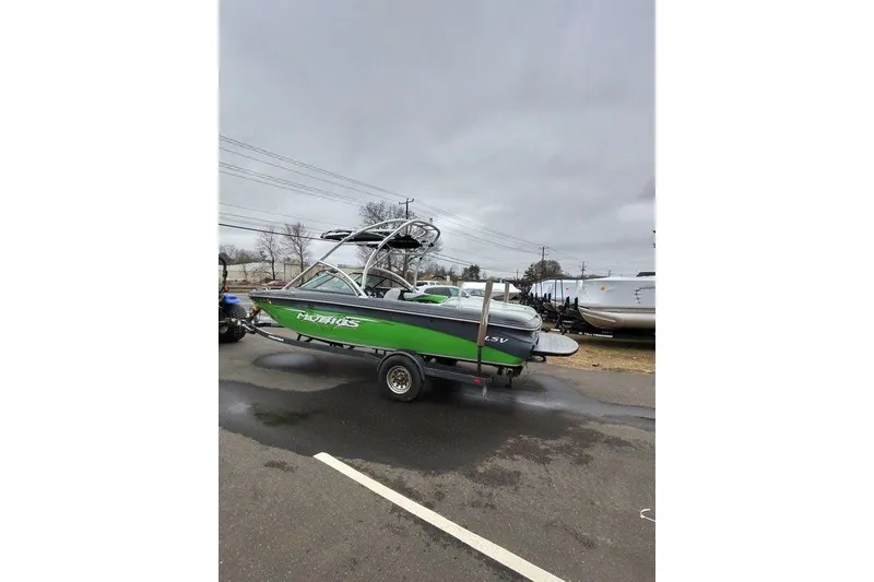 Slide: The Image of 2009 Moomba Mobius LSV boat in green on a trailer, parked outdoors. - 7