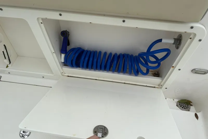 Slide: The Image of Storage compartment with blue coiled hose on a 2017 Century 2600 Center Console boat. - 13