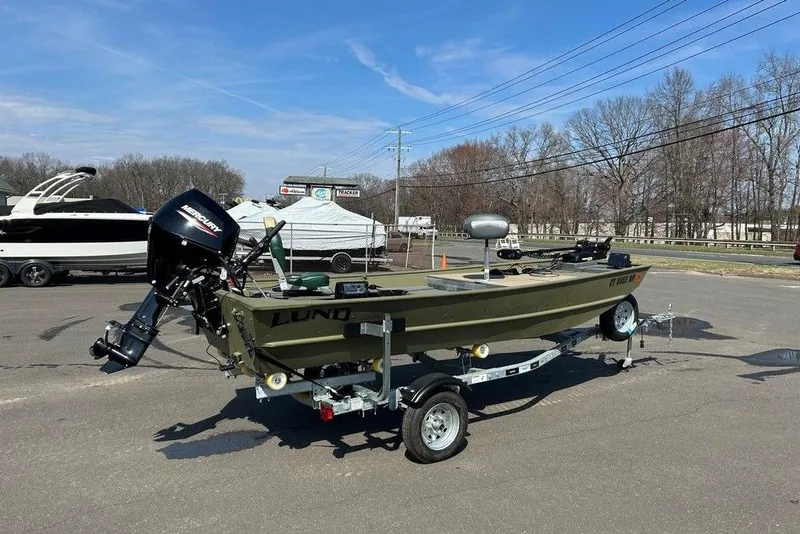 Slide: The Image of 2024 Lund UR1448MTD boat on trailer with Mercury outboard motor, parked outdoors. - 4