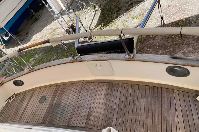 Slide: The Image of 1988 Albin 43 Trawler deck with wooden flooring and railing, docked on land. - 14