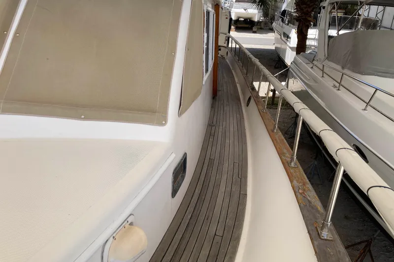 Slide: The Image of 1988 Albin 43 Trawler side deck with wooden railing and beige covers. - 9