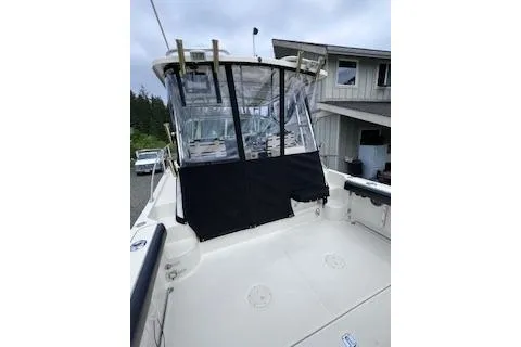 Slide: The Image of 2005 Pursuit 3070 Offshore boat with covered cockpit, docked near a house. - 15