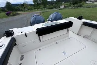 Slide: The Image of 2005 Pursuit 3070 Offshore boat deck with dual engines, parked on grassy area. - 16