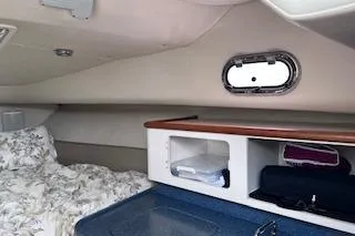 Slide: The Image of 2005 Pursuit 3070 Offshore cabin interior with bed, storage, and porthole window. - 8