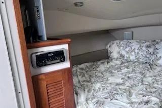 Slide: The Image of 2005 Pursuit 3070 Offshore cabin interior with bed and wooden cabinet. - 9