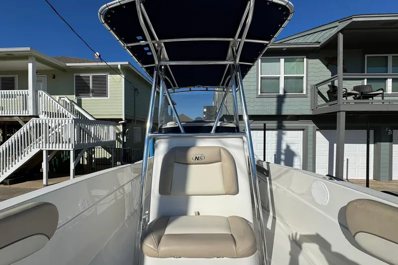Slide: The Image of 2016 NauticStar 231 Coastal boat with T-top, parked near coastal homes. - 10