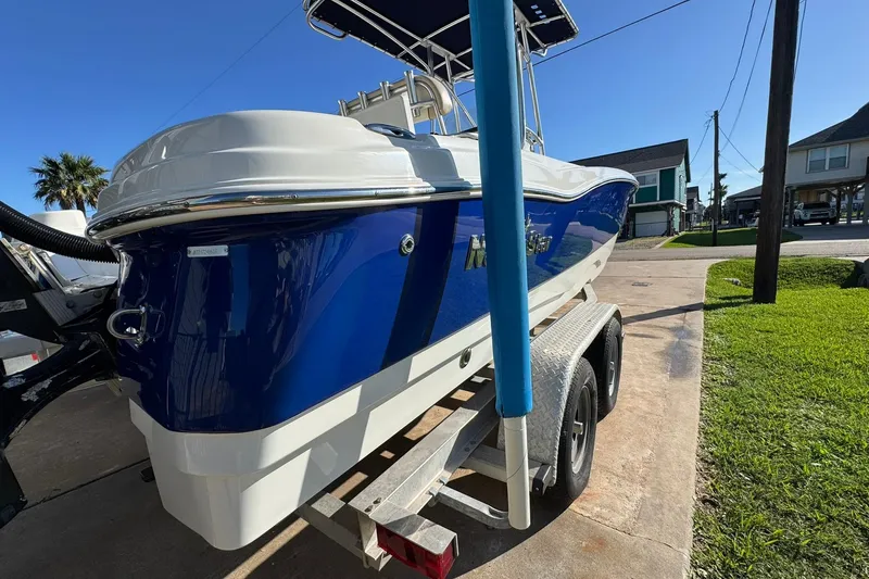 Slide: The Image of 2016 NauticStar 231 Coastal boat on trailer, parked outdoors under clear blue sky. - 3