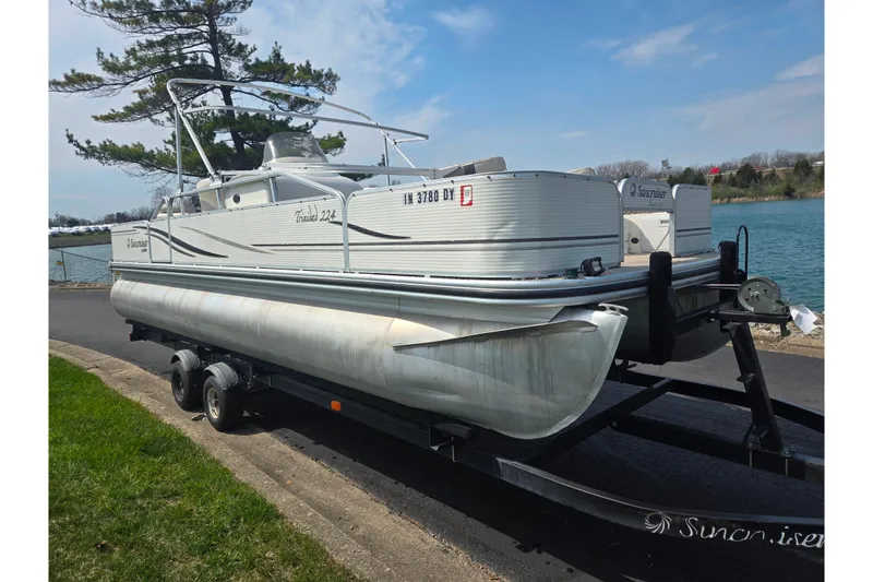Slide: The Image of 2006 Suncruiser Trinidad 220 pontoon boat on trailer by a lakeside road. - 8