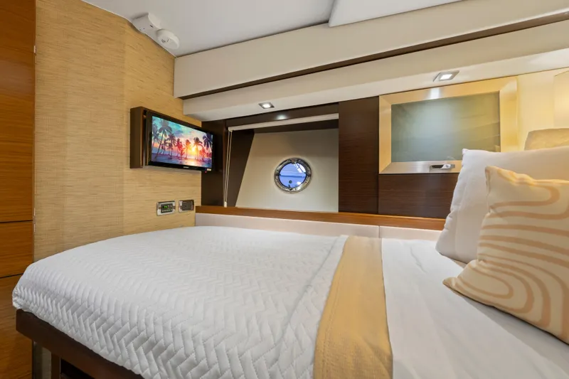 Slide: The Image of 2015 Tiara Yachts interior cabin with bed, porthole, and wall-mounted TV. - 48