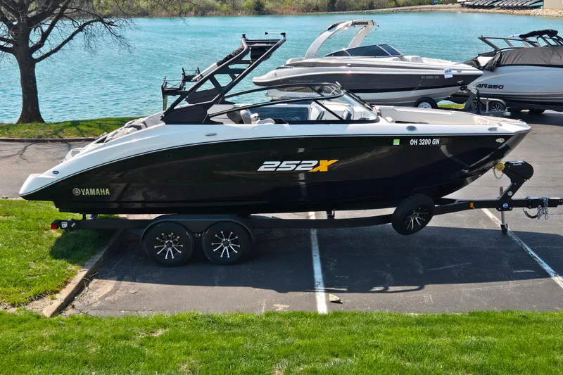 The Image of 2023 Yamaha Boats 252XE on trailer by a lake, showcasing sleek design and modern features. - 0