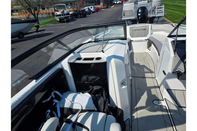 Slide: The Image of 2023 Yamaha Boats 252XE interior with seating and storage, parked outdoors. - 12