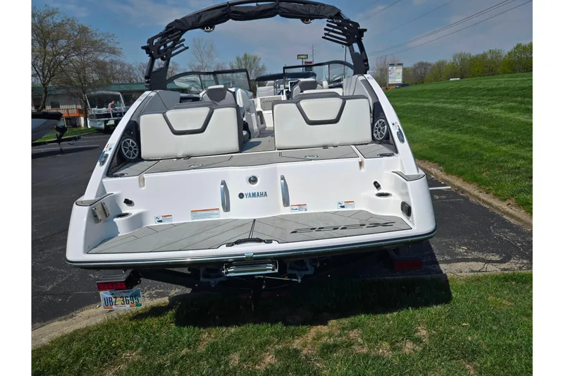 Slide: The Image of 2023 Yamaha Boats 252XE, rear view, parked on grass, showcasing sleek design and seating. - 2