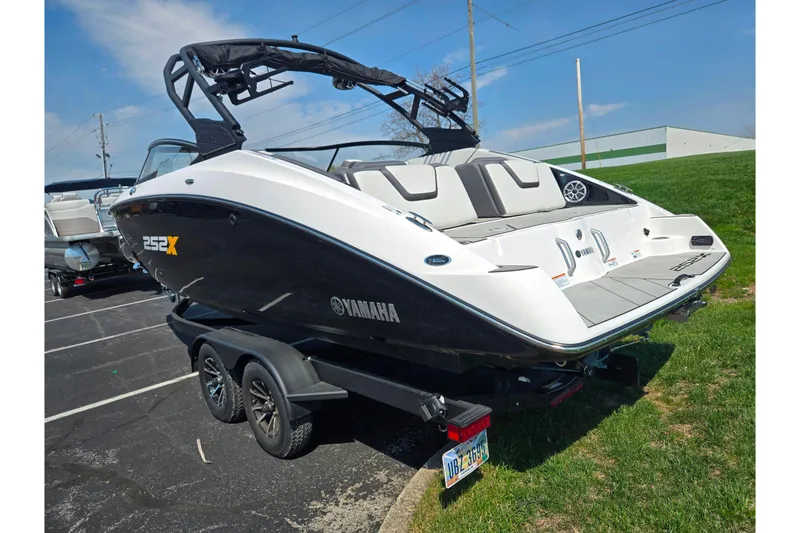 Slide: The Image of 2023 Yamaha Boats 252XE on trailer, sleek design, parked outdoors under blue sky. - 3