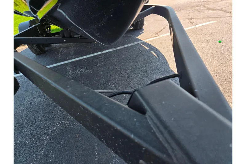 Slide: The Image of 2023 Yamaha Boats 252XE trailer detail, showing frame and parking lot surface. - 7