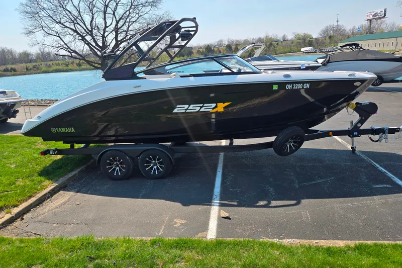 Slide: The Image of 2023 Yamaha Boats 252XE on trailer by a lake, showcasing sleek design. - 9