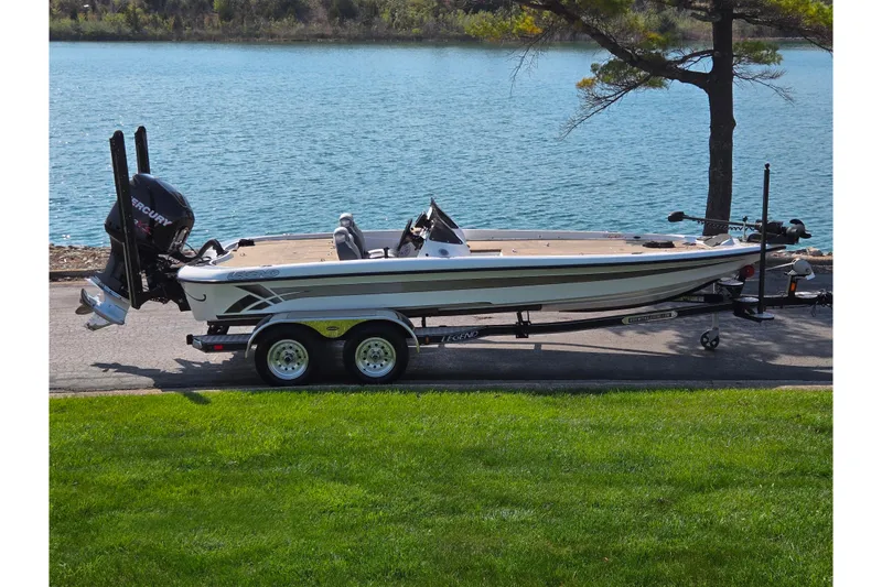 The Image of 2016 Legend Alpha 211R DC fishing boat on trailer by a lake. - 0