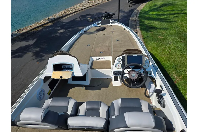 Slide: The Image of 2016 Legend Alpha 211R DC boat interior with steering wheel and seating near a lakeside. - 11