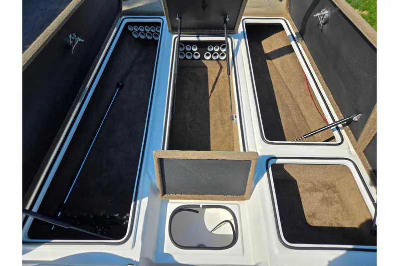 Slide: The Image of 2016 Legend Alpha 211R DC boat storage compartments with rod holders and carpeted interiors. - 16