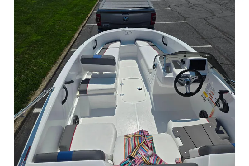 Slide: The Image of 2024 Tahoe T16 boat interior with seating, steering wheel, and dashboard in a parking lot. - 10