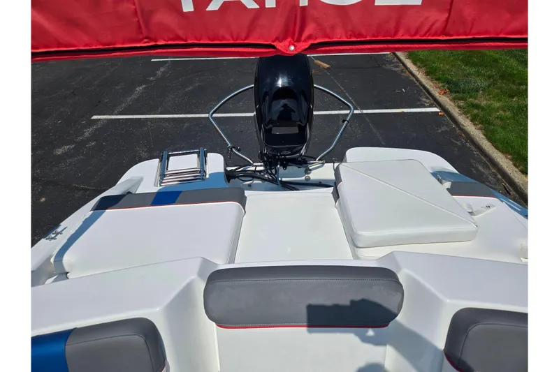 Slide: The Image of 2024 Tahoe T16 boat interior with seating and motor, parked on asphalt. - 21