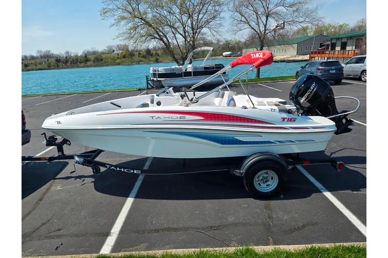 Slide: The Image of 2024 Tahoe T16 boat on trailer by a lake, featuring sleek design and vibrant graphics. - 9