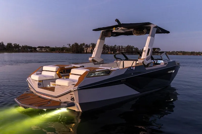 Slide: The Image of Manufacturer Provided Image: 2026 Nautique Super Air Nautique G25 Paragon boat illuminated on calm water at dusk. - 35