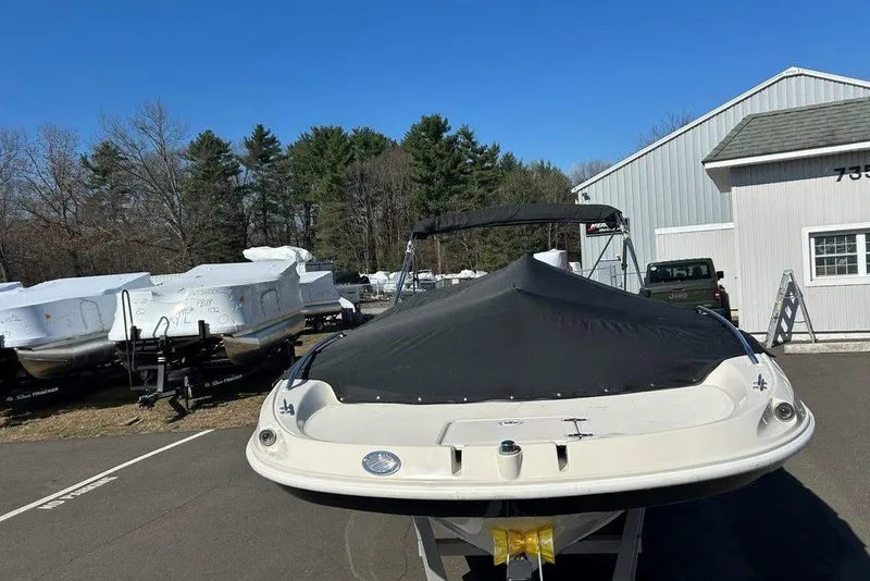 Slide: The Image of 2009 SouthWind 210 SD boat covered, parked near other boats and a building. - 4
