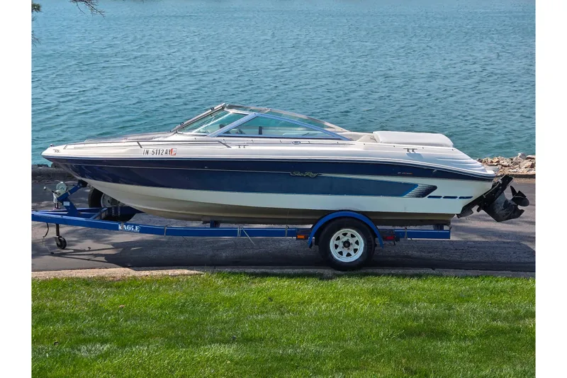 The Image of 1994 Sea Ray 180 Bow Rider boat on trailer by a lake. - 0