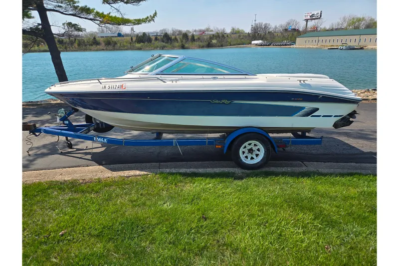 Slide: The Image of 1994 Sea Ray 180 Bow Rider boat on trailer by a lake, sunny day. - 10