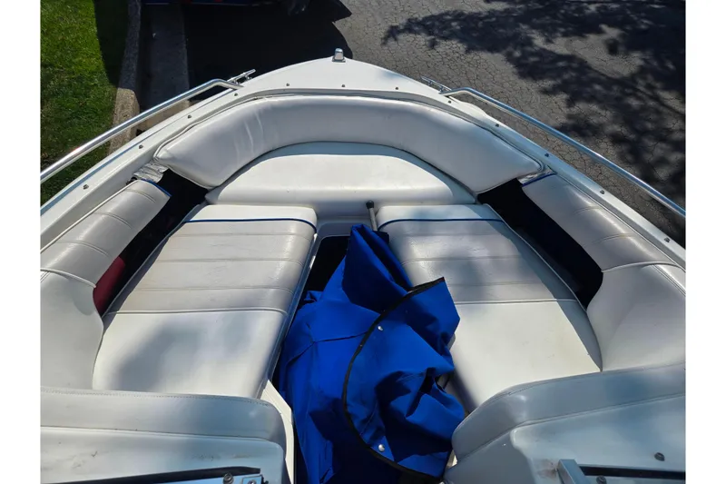 Slide: The Image of 1994 Sea Ray 180 Bow Rider interior with white seating and blue cover. - 17