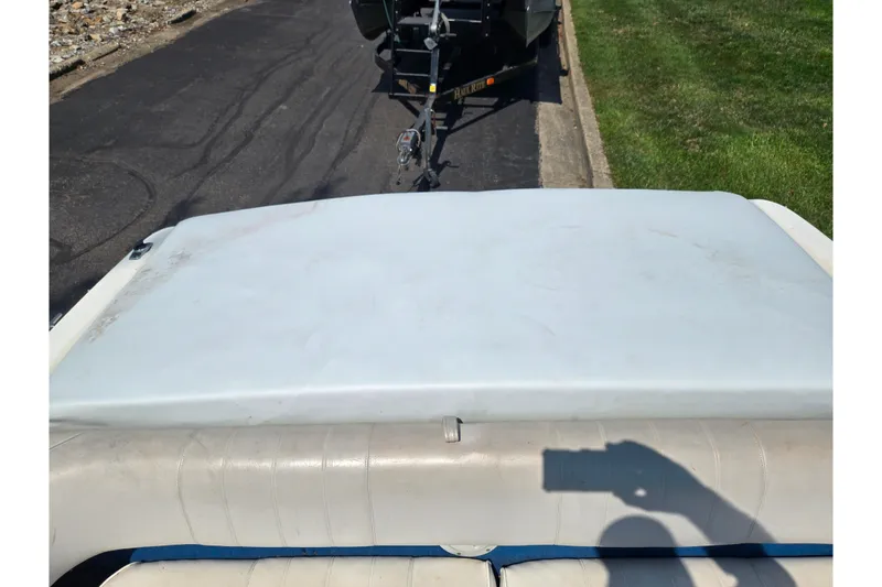 Slide: The Image of 1994 Sea Ray 180 Bow Rider boat interior with white upholstery and trailer in background. - 23