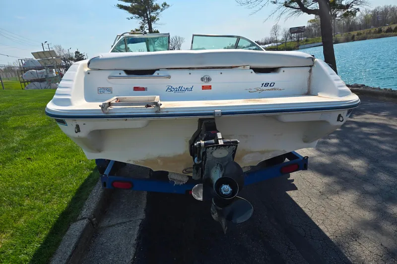 Slide: The Image of 1994 Sea Ray 180 Bow Rider boat on trailer by a lake. - 3