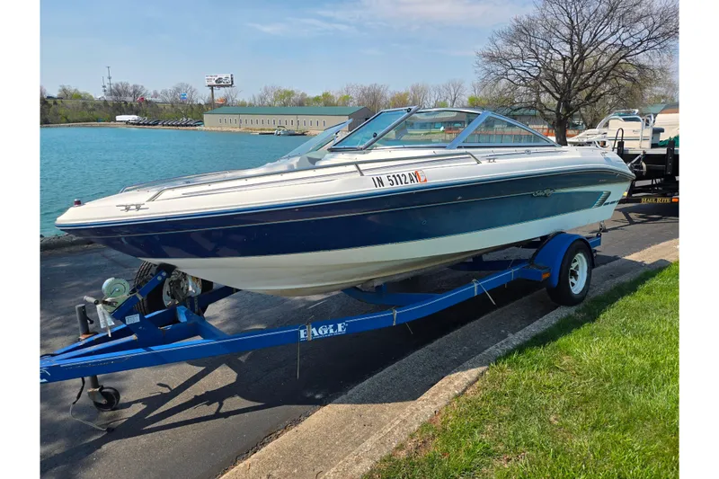 Slide: The Image of 1994 Sea Ray 180 Bow Rider on trailer by a lake, ready for boating. - 9
