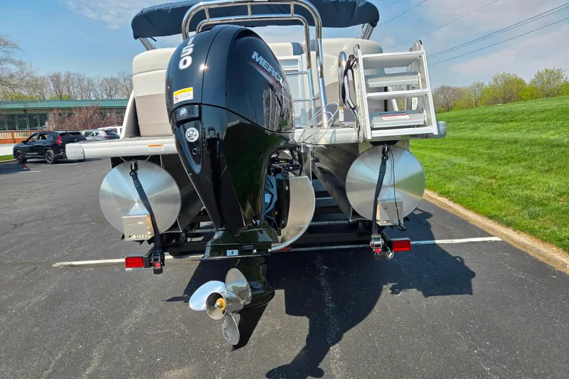 Slide: The Image of 2025 Godfrey Sweetwater 2286 QS pontoon boat with Mercury outboard motor in parking lot. - 2